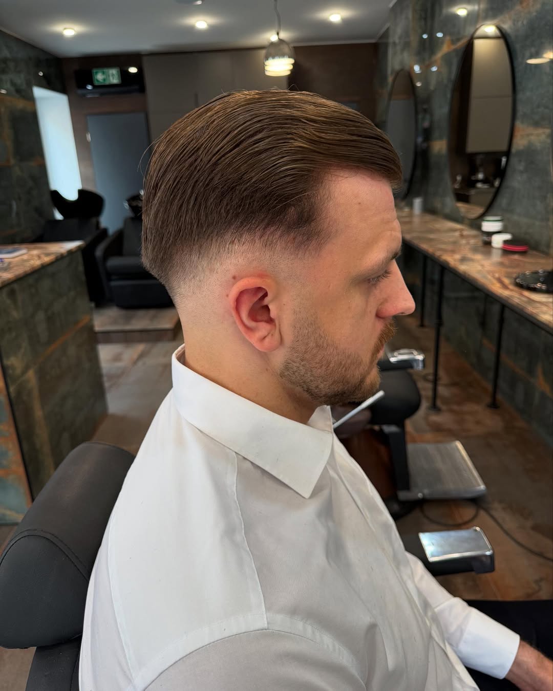 Innenraum des Cla$$ic Barbershop Hagen mit runden Spiegeln und warmem Licht